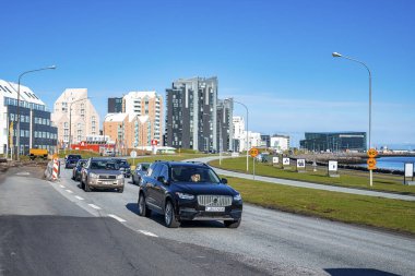 Araçlar binaların ve tabelaların arasında yolda ilerliyor. Güneşli bir günde şehir caddelerinde açık mavi gökyüzüne karşı arabalar. Kuzey Alp bölgesindeki kentsel manzara.