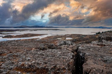 Göl kenarındaki güzel kaya oluşumlarının manzarası. Manzaralı manzara ve bulutlu gökyüzüne karşı dağlar. Kuzey Alp Bölgesi 'nde gün batımında resimli manzaranın ideal görünümü.