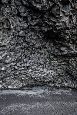Bazalt kaya sütunlarının manzarası. Sahil bölgesindeki siyah deniz kıyısındaki desenli taşlara dair idealist bir bakış açısı. Ünlü Reynisfjara Sahili 'ndeki görkemli uçurum..