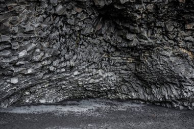 Siyah deniz kıyısında güzel bazalt sütunlar oluşmuş. Atlantik kıyı bölgesindeki desenli taşların ideal görüntüsü. Ünlü Reynisfjara Sahili 'ndeki görkemli uçurum manzarası..