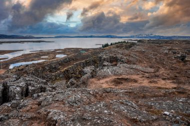 Göl kenarındaki cennet gibi kaya oluşumlarının manzarası. Resimli manzara ve bulutlu gökyüzüne karşı dağlar. Kuzey Alp bölgesinde gün batımında güzel manzara.