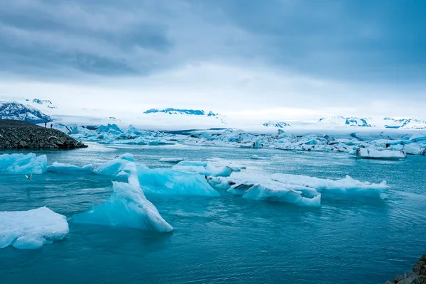 冰川湖中漂浮着美丽的冰山 在多云的天空下 冰川冰层的景观 极地气候条件下的约库尔沙隆冰川泻湖岩溶景观 — 图库照片