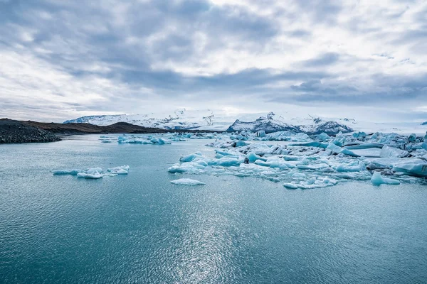 ジョクルサロン氷河ラグーンに浮かぶ氷山の景色 曇った空に対して湖の美しい氷河の形成 極端な気候の間にVatnajokullの牧歌的な風景 — ストック写真