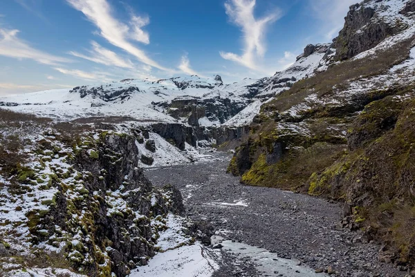 溪流在白雪覆盖的山间奔流 火山谷相对于天空的冰冠岩层景观 冰岛冬季美丽的风景 — 图库照片