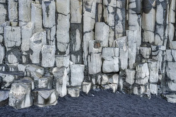 Beautiful basalt columns formation on black seashore. View of patterned stones in Atlantic coastal region. Scenic view of majestic cliff at famous Reynisfjara Beach.