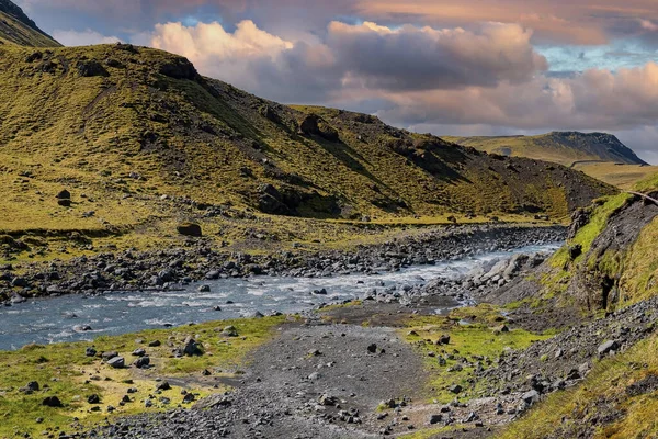 緑の風景の中を流れる美しいストリーム 火山谷の山の範囲の風景 日没時のセジャベラーの曇り空に対する水の実行中の牧歌的なビュー — ストック写真