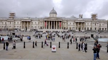 Londra 'daki Trafalgar Meydanı' nda yoğun bir öğleden sonra. Meydanı ve Ulusal Galeri 'yi ziyaret eden yerli ve turistler. 4k video.