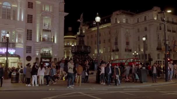 伦敦皮卡迪利马戏团的夜生活穿过街道的人们和带有广告牌的标志性红色双层巴士驶过皮卡迪利广场 — 图库视频影像