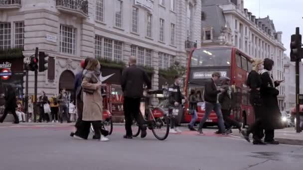 ロンドン市内中心部での交通量が多い ロンドンのLillywhiteの建物による歩道の歩行者とピカデリーサーカスを横断する車と赤いバス — ストック動画