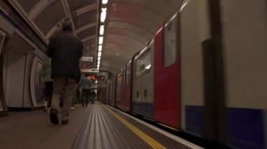 Londons metro istasyonundaki yolcularla birlikte tren peronunda. Londra metro 4k video.