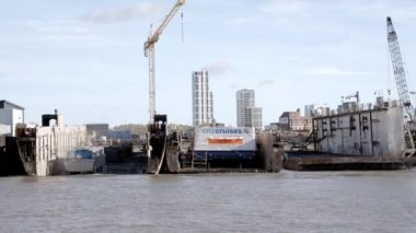 Nehirdeki tekneler rıhtımda, inşaat vinçleri ve bulutlu gökyüzüne karşı şehir manzarası olan tekneler. Londra 'da rıhtım, Londra' da tekne tamiri..