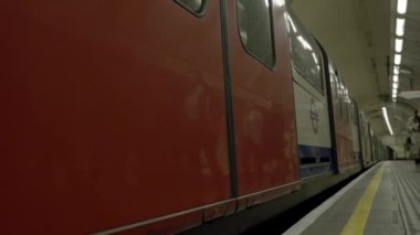 Londons metro istasyonundaki yolcularla birlikte tren peronunda. Londra metro 4k video.