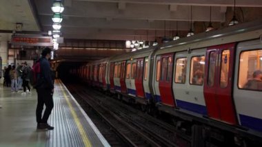 Londons metro istasyonundaki yolcularla birlikte tren peronunda. Londra metro 4k video.