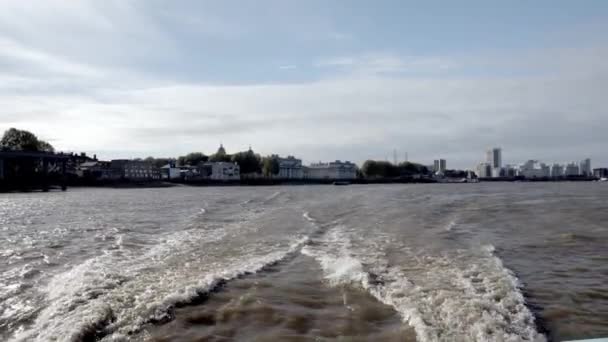 曇りの空を背景にした街並みでテムズ川沿いのボートトラック 川のボートの後ろにある薄汚い道 ロンドンのテムズ川を航海中 — ストック動画