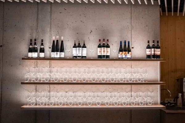 Duvara Karşı Raflarda Çeşitli Alkollü Şişeler Sergileniyor Şarap Kadehleri Aydınlatılmış — Stok fotoğraf