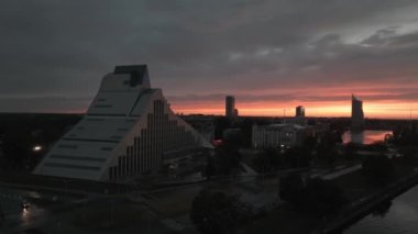 Riga 'daki Letonya Ulusal Kütüphanesi' nin destansı günbatımında hava görüntüsü. Riga üzerinde gece görüşü.