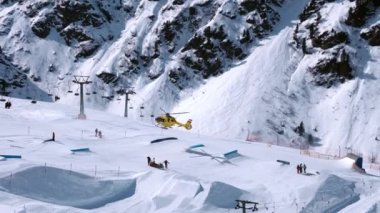 Kurtarma helikopteri yamaçlara iniyor kayakçıya kayak parkında yardım ediyor. Alplerdeki hava ambulansı. Kurtarma aracı.