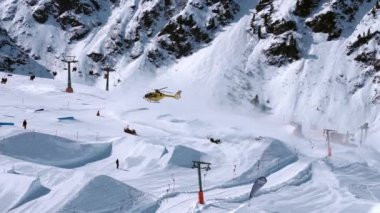 Kurtarma helikopteri yamaçlara iniyor kayakçıya kayak parkında yardım ediyor. Alplerdeki hava ambulansı. Kurtarma aracı.