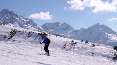 Erkek kayakçı gökyüzüyle yamaçlara çıkıyor. Alpler 'de güneşli bir günde manzaralı dağ sıraları. Turist kış boyunca maceradan zevk alıyor..
