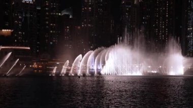 Dubai 'de gece vakti Burj Halife gökdeleninin önünde fıskiye gösterisi. Burj Halife binasının önündeki çeşmeler. 4k video.
