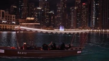 Dubai 'deki Burj Halife gökdeleninin önündeki geleneksel tekne. Burj Halife binasının önündeki çeşme gösterisini bekliyorum..