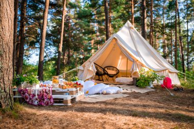 Boho tarzında güzel beyaz bir dekor. Doğada piknik, masa, halılar, çadır, parkta yastıklar. Doğa konseptinde tatiller.