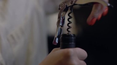 Bir kadının elleri tirbuşonla beyaz şarap şişesini açıyor. 4K 'lık bir videoda şarap şişesi ve mantarı kapat.. 