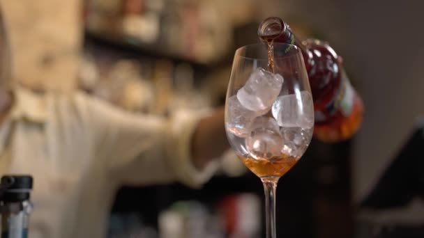 准备一杯Aperol Spritz鸡尾酒在酒杯中倒入冰块 在鸡尾酒中洒上桔子精油 喝了一大杯 — 图库视频影像