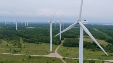 Aerial view of powerful Wind turbine farm for energy production on beautiful cloudy sky at highland. Wind power turbines generating clean renewable energy for sustainable development. 4k footage.