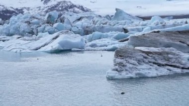 Buzdağlarının buzul gölünde yüzdüğü güzel bir manzara. Buzul oluşumlarının manzaralı görüntüsü. İzlanda 'daki Jokulsarlon buzullu gölünün Idyllic manzarası. Güzel İzlanda doğası.