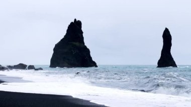 Fırtınalı Atlantik Okyanusu 'nun görkemli yeri. Bazalt kaya - Troll ayak parmakları. Reynisfjara Sahili, İzlanda, Avrupa. Popüler Avrupa seyahatlerinin video görüntüleri. İzlanda 'nın güzel doğası.