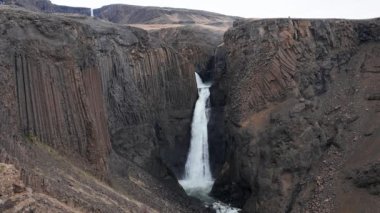Litlanesfoss şelalesi daha uzun Hengifoss şelalesine giden yolda bazalt sütunlarla çevrili, Doğu İzlanda 'nın günbatımındaki ünlü turistik manzarası.