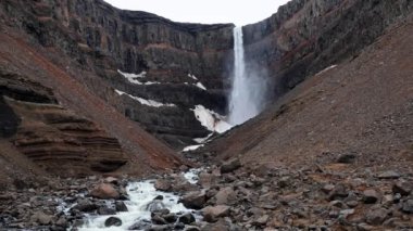 Litlanesfoss şelalesi daha uzun Hengifoss şelalesine giden yolda bazalt sütunlarla çevrili, Doğu İzlanda 'nın günbatımındaki ünlü turistik manzarası.
