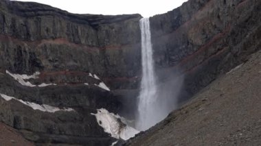 Litlanesfoss şelalesi daha uzun Hengifoss şelalesine giden yolda bazalt sütunlarla çevrili, Doğu İzlanda 'nın günbatımındaki ünlü turistik manzarası.