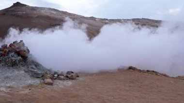 Steam emitting from fumarole in geothermal area of Hverir. Sulphur dioxide erupting from volcanic crater at Namafjall. Geyser in famous tourist attraction in Iceland.
