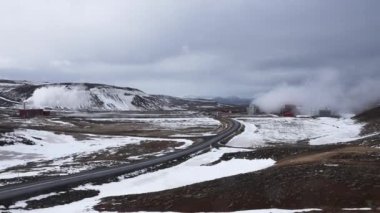 İzlanda 'daki Krafla jeotermal santralindeki buharlı soğutma kulesinin görüntüsü. İzlanda 'nın en büyük enerji santralinden buhar yayılıyor. Volkanik vadideki kar manzarası.