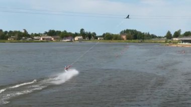 Wakeboardcu gölde sörf yapıyor ve vuruculardan atlıyor. Havadan wakeboard çekimleri. 