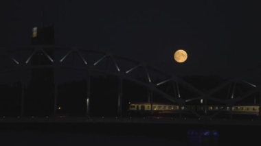 Full moon over Riga with a night train crossing river Daugava. Night Riga.