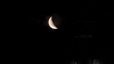 Beautiful quarter moon over Riga old town behind Domes cathedral clock. Night sky with amazing moon timelapse.