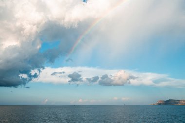Gökyüzündeki bulutların arasından bakan güzel gökkuşağının manzarası. Güneşli bir günde deniz manzaralı Idyllic deniz manzarası. Ünlü turistik yerlerdeki limanda nefes kesici doğa kavramı.
