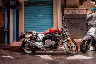 Catalina, Sicilya, İtalya. 26 Ağustos 2022. Kapalı dükkanın önünde motosiklet park edilmiş. Güneşli bir günde caddede şık bir araç. Yaz boyunca şehirdeki eski dükkanlar.