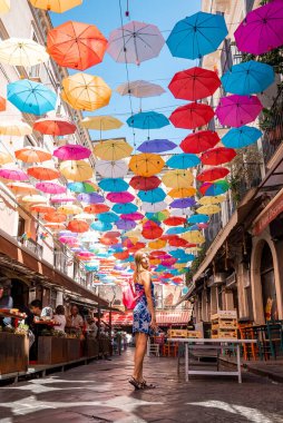 Catalina, Sicilya, İtalya. 26 Ağustos 2022. Caddenin üzerinde, çok renkli şemsiyelerin altında, kafenin yanında duran kadının portresi. Dişi turist yaz boyunca şehirde güzel bir dekorasyonla eğleniyor..