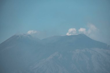 Güzel volkanik Etna Dağı duman yayıyor. Arka planda mavi gökyüzü olan ünlü turistlerin manzarası. Yaz boyunca kraterli görkemli dağlar.