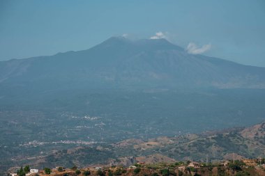 Önünde şehir manzarası olan görkemli Etna Dağı. İnsan yerleşimi ve arkasında mavi gökyüzü olan aktif volkanik krater. Yaz boyunca ünlü varış yeri manzarası.