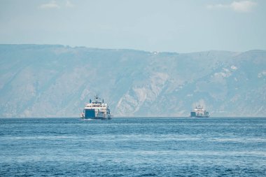 Messina, Sicilya, İtalya. 26 Ağustos 2022. Gemi deniz manzarasında hareket ediyor. Akdeniz limanında eski liman kenti Messina 'daki dağlara karşı arka planda gökyüzü olan deniz gemileri.