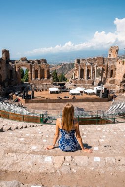 Antik Yunan tiyatrosunun kalıntılarında dinlenen bir kadın. Güneşli bir günde ünlü bir gösteriye bakan kadın turist. Giardini Naxos Körfezi 'nde yaz tatilinin tadını çıkarıyor..