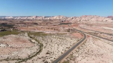 Kuzey Arizona otoyolu, kırmızı kayalar ve manzaranın içinden geçiyor. Hava 4K videosu. Anıt Vadisi yakınlarındaki Amerika 'ya güzel bir yolculuk..