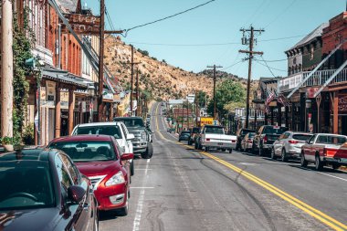 Virginia, ABD. Yazın eski binaların arasında yol manzarası. Virginia kovboy kasabasında arka planda dağ ve mavi gökyüzü olan dükkanlar ve elektrik kolonları.