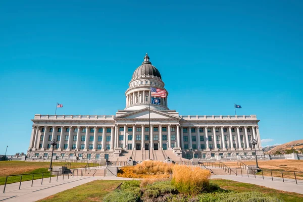 Garden at entrance of State Capitol building in Salt Lake city. View of national government built structure with clear blue sky in background. Famous political landmark in city during sunny day.