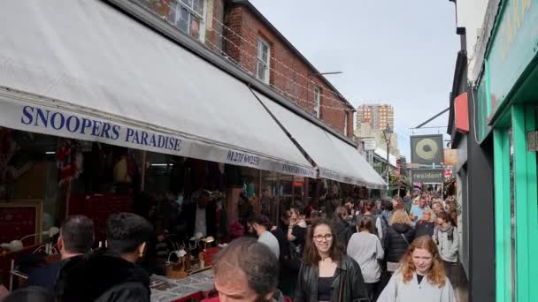 人々や観光客が小さなお店やレストランを訪れるブライトンの狭い通りを歩いています トラファルガー通りを歩くブライトンビーチイギリス — ストック動画